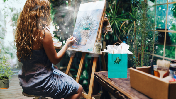 stoner chick artist at easel working on weed art in a cloud of smoke with a gift bag